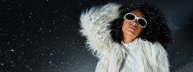 A stunning African American woman showcases winter fashion in a chic white ski suit and faux fur jacket. clipart