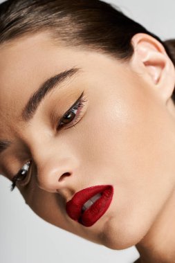Çarpıcı kırmızı dudaklı bir kadın büyüleyici özelliklerini ve kusursuz makyajını sergiliyor..