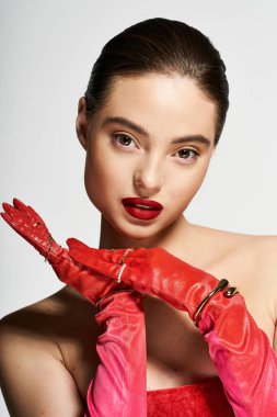 A confident woman poses gracefully in vibrant red gloves and striking lipstick, exuding charm. clipart