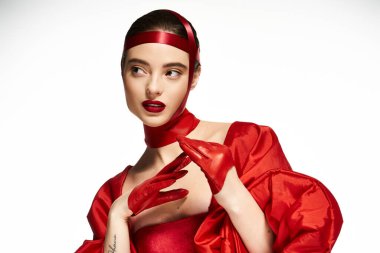 Çarpıcı kadın canlı kırmızı bir şekilde poz verirken kendine güveni tam..