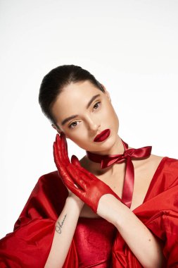 Kırmızılı çekici bir kadın zarifçe poz veriyor, zarafetini ve tarzını vurguluyor..