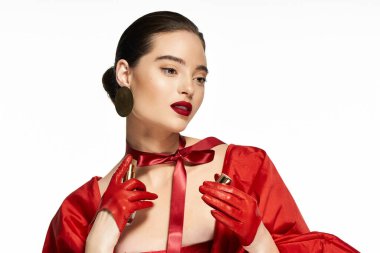 Çekici bir kadın canlı kırmızı bir elbise giyer ve zarif bir şekilde güzel eşyalar sunar..