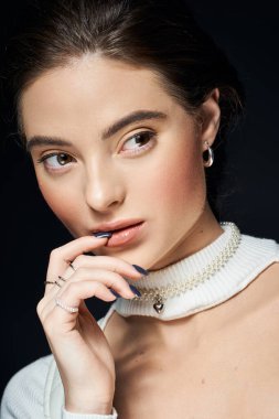 Çekici bir kadın zarif bir ifade ve zarif bir takı ile zarifçe poz verir..