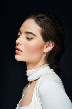 Zarif bir kadın karanlık bir arkaplan karşısında sakin bir ifade sergiler, özelliklerini vurgular..