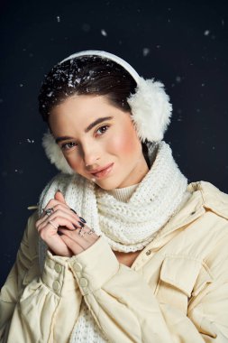 Çekici bir kadın nazikçe gülümser, sıcak bir eşarba sarılmış, yağan karla çevrili..