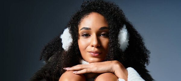 A beautiful brunette woman wears earmuffs and a faux fur jacket, embodying winter fashion trends in a studio.