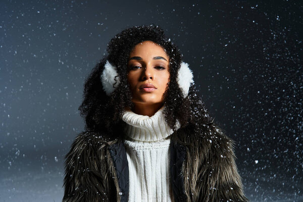 A beautiful brunette woman dons earmuffs and a faux fur jacket, exuding winter fashion elegance in the studio.