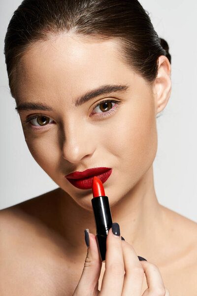 A beautiful woman enhances her look with bold red lipstick in a stylish environment.