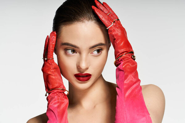 Модная женщина изящно позирует, подчеркивая свои яркие красные перчатки и художественный макияж.