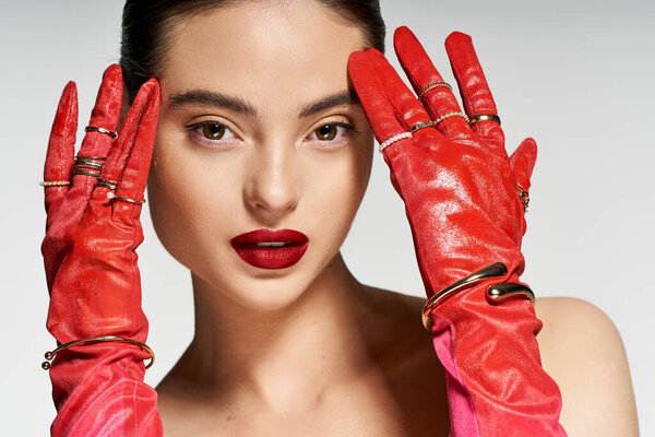 Уверенная женщина демонстрирует модные красные перчатки и смелый макияж губ в шикарной атмосфере.