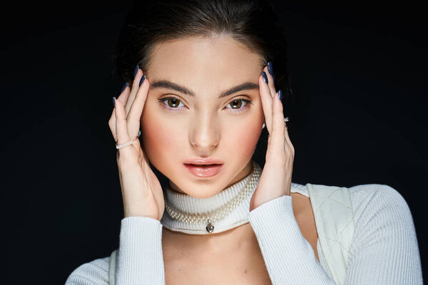 Удивительно красивая женщина нежно касается своего лица, излучая элегантность и артистичность..