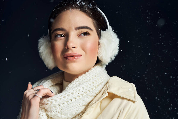 Улыбающаяся женщина в теплой одежде наслаждается снежным моментом, окруженная мягкими падающими снежинками.