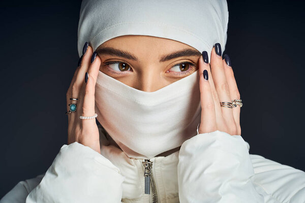 Женщина изящно позирует, прижав руки к лицу, подчеркивая свой изысканный стиль..