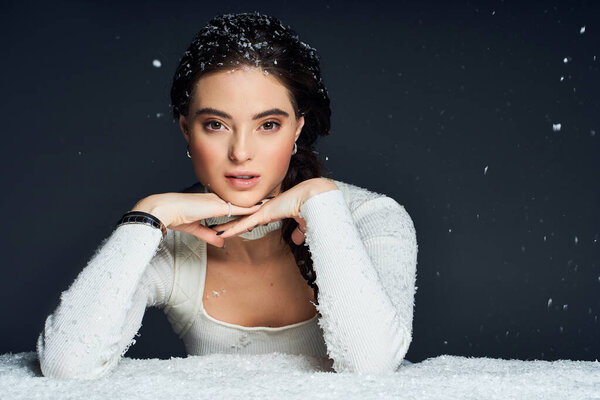 The beautiful woman gazes thoughtfully as snowflakes dance around her in a tranquil setting.