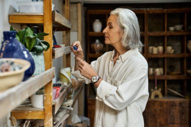 Sıcak bir stüdyoda, bir kadın sanat malzemelerini düzenler, yaratıcı ruhunu gözler önüne serer..