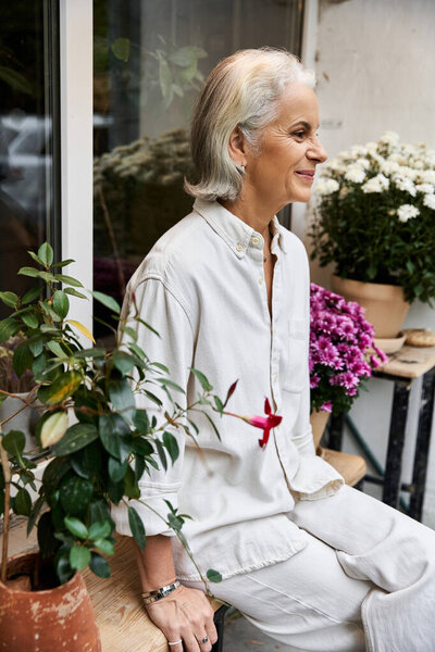 A graceful woman sits beside colorful blooms, enjoying a peaceful afternoon in natures embrace.