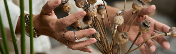 A beautiful mature woman carefully arranges dried flowers, showcasing her artistic talent.