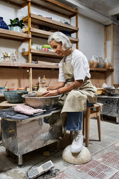 A talented artisan focuses intently on molding clay, enveloped in a warm and inspiring workspace.