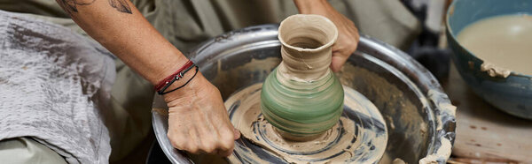 Опытная женщина создает красивую зеленую вазу на гончарном круге в уютной студии.