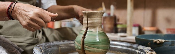 A talented artisan focuses on shaping a clay vase with intricate designs in her workspace.