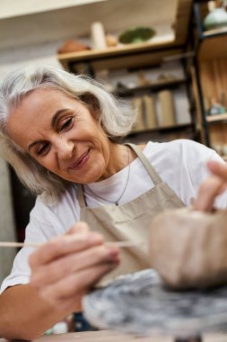 Yetenekli bir sanatçı, sıcak ve davetkar bir atölyede gülümserken kilden bir eser ustalıkla hazırlar.