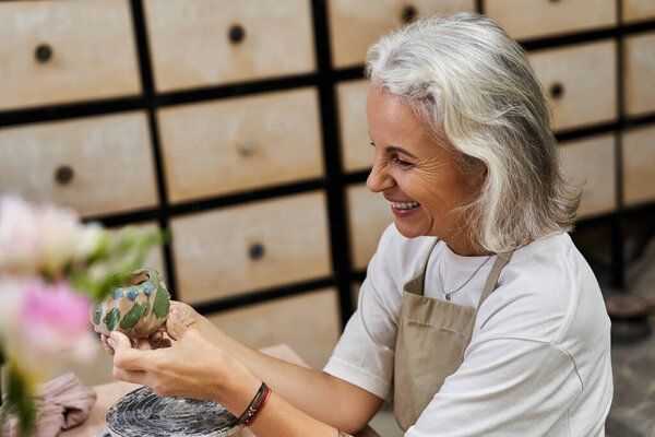 An experienced woman joyfully creates a beautiful pottery item in her inviting workspace