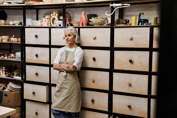 A skilled artisan reflects on her craft while surrounded by vibrant ceramics and tools.
