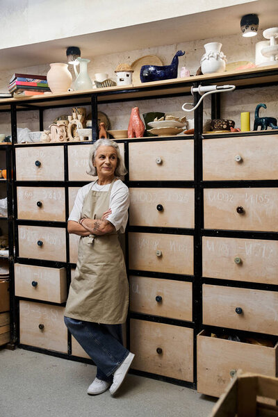 A graceful mature woman stands confidently in her studio, embracing her passion for pottery.
