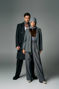 Genç ve çekici bir ikili, modern bir stüdyo ortamında hafif ışıklandırmalı moda giysiler sergiliyor..