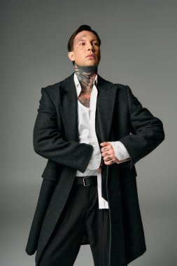 A stylish young person flaunts a dark coat and striking tattoos. clipart