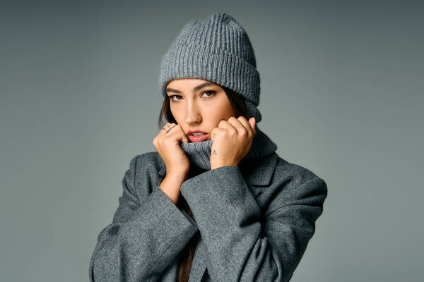 Молодая и привлекательная женщина модели моды в уютном сером наряде, демонстрируя свой стиль.