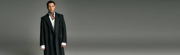 The young man stands tall, exuding charisma in a chic long coat fitting the modern aesthetic.