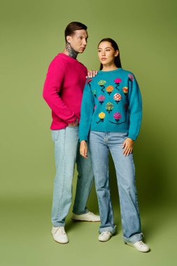 A stylish young couple stands together, showcasing vibrant knitwear while smiling warmly. clipart