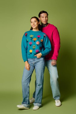 Two stylish individuals in vibrant sweaters share a fun fashion moment. clipart