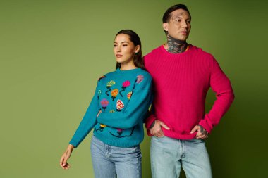 Şık, genç bir çift, kendine güvenen bir ortamda dururken eşsiz süveterler sergiliyor..