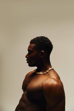 Genç, çarpıcı Afrikalı Amerikalı bir adam yaratıcı bir iç mekan ortamında üstsüz poz veriyor, kendinden emin ve çekici..