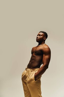 A young, handsome African American man showcases his well defined physique while standing confidently topless. Dressed in tailored pants, he strikes a poised pose that radiates charisma and style. clipart