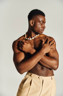 Genç ve yakışıklı bir Afro-Amerikan erkeği kendinden emin bir şekilde duruyor..