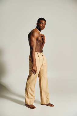 Genç, yakışıklı bir Afro-Amerikan adam minimalist bir stüdyoda güvenle duruyor..
