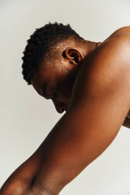 Genç bir Afrikalı Amerikalı üstsüz poz veriyor, kaslı fiziğini ve kendine olan güvenini gösteriyor..