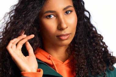 Kendine güvenen bir kadın çekici özelliklerini ve güzel kıvırcıklarını çekici bir pozda sergiliyor..