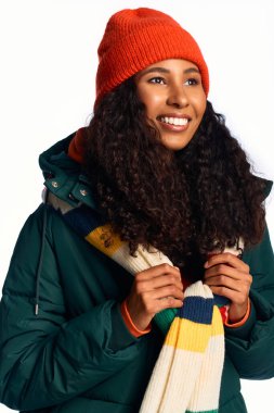 Neşeli bir kadın kışın keyfini çıkarırken canlı bir eşarp ve rahat bir ceket giyer, mutluluk saçar..