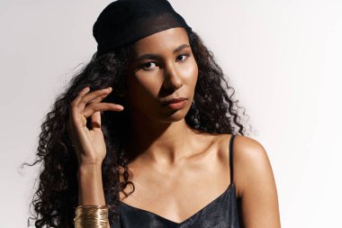 Kıvırcık saçlı, kendine güvenen bir kadının portresi, yumuşak ışıkta zarifçe poz verir..