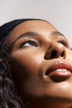 Zarif kadın yukarı bakıyor, parlak cildini ve çarpıcı özelliklerini sergiliyor..