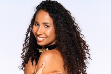 Kıvırcık saçlı kadın neşe ve kendine güven saçar ve neşeli bir ortamda gülümser..