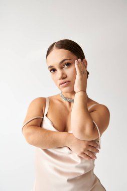 Kısa boylu model zarif bir elbiseyle poz veriyor, kapsama ve stili vurguluyor..