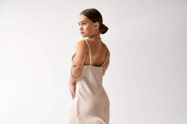 Kısa boylu genç bir kadın zarif bir şekilde poz veriyor. Güzel bir elbise içinde, çeşitliliği vurguluyor..