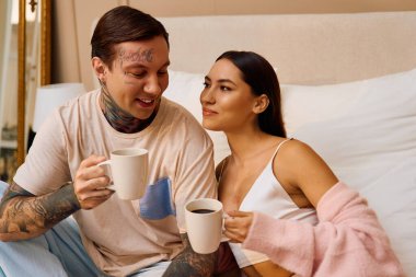 A young couple shares a tender moment while sipping coffee and gazing into each others eyes. clipart