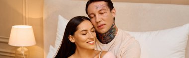 Genç bir çift, huzurlu bir yatak odası ortamında sevgi ve mutluluk saçan şefkatli bir kucaklaşmadan hoşlanır..