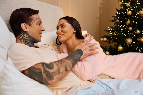 A loving couple shares sweet smiles while relaxing on a couch surrounded by holiday spirit.